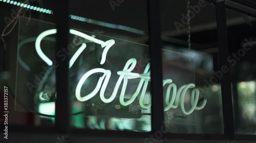 Blue Tattoo Light Sign on a Window From a Barbershop and Tattoo Studio