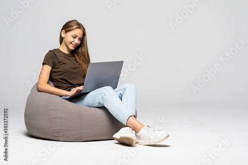 Wallpaper Mural Happy young woman sitting on the floor using laptop on gray background Torontodigital.ca