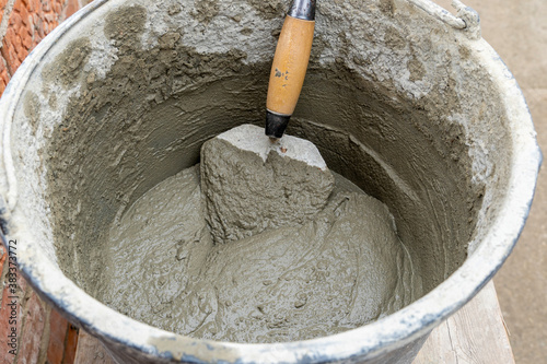 Cement-sand concrete mix in a plastic bucket with a trowel