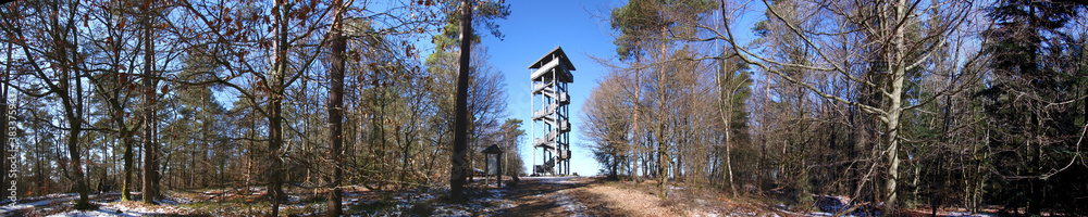 Panoramic view of a wooden lookout tower in a winter forest with snow covered trees in the Eifel mountains near Dierscheid, Germany