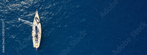Aerial drone ultra wide photo of sailboat anchored in island of Santorini, Cyclades, Greece © aerial-drone