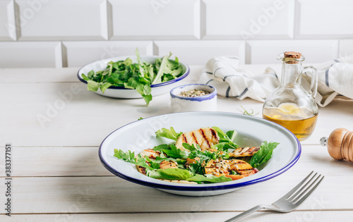 Grilled Halloumi Cheese salad with peach and arugula on a white wooden background. Healthy food concept.