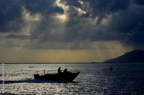 Un bateau passe au coucher du soleil face    Moorea sous un ciel orageux    Punaauia en Polyn  sie Fran  aise