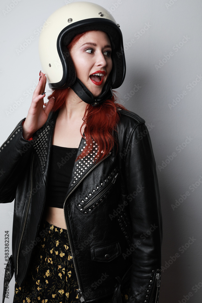 Portrait of young woman with a motorcycle helmet posing over isolated white background celebrating a victory. Portrait of young woman with a motorcycle helmet posing over isolated white background celebrating a victory.