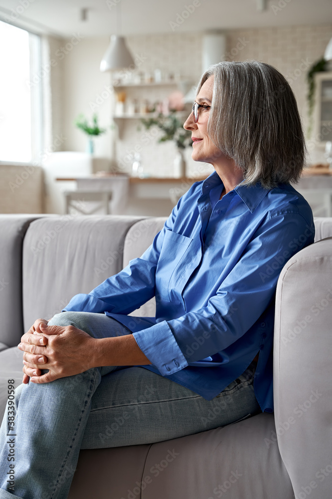 Classy relaxed mature old woman relaxing sitting on couch at home. Peaceful  middle aged grey-haired