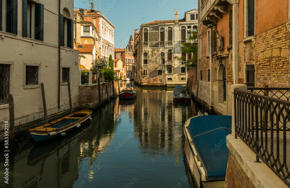 Venice canal with boats and blue sky in sunshine