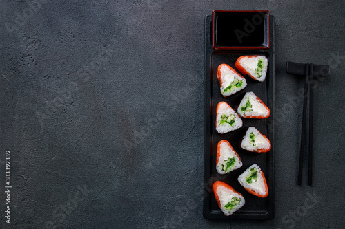 Japanese food, sushi restaurant. Salmon maki sushi rolls on black plate, flat lay. Seafood background