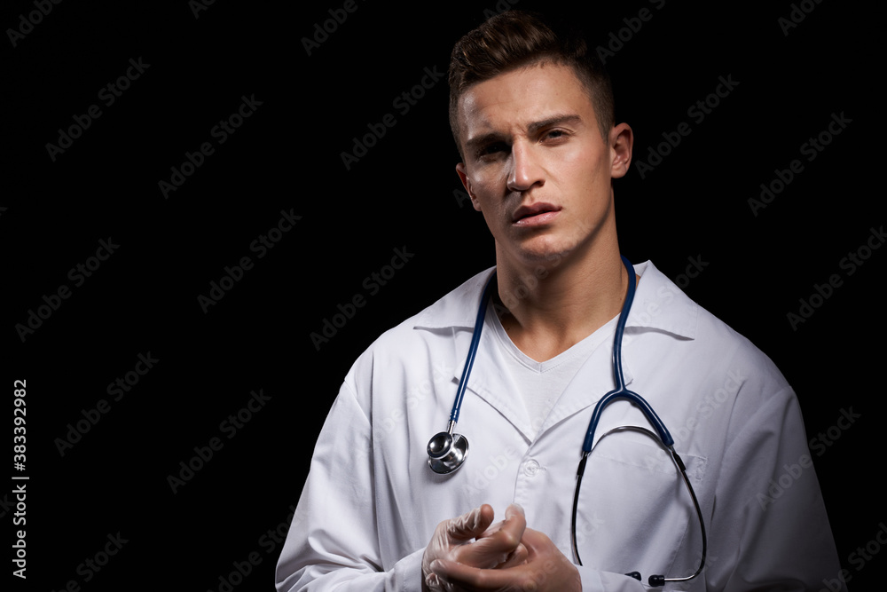 professional doctor in a medical gown with a stethoscope around his neck against a dark background cropped view professional doctor in a medical gown with a stethoscope around his neck against a dark background cropped view