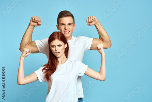strong man showing arm muscles on blue background and young woman cropped view
