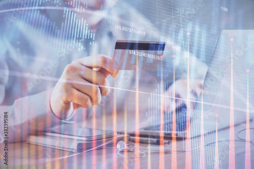 Double exposure of man hands holding a credit card and Forex graph drawing. Stock trading and digital fintech in Internet E-commerce concept.