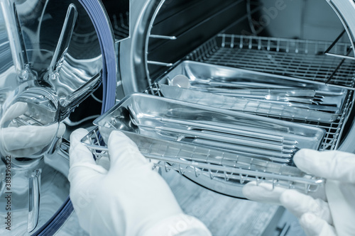 Female nurse doing sterilization of dental medical instruments in autoclave. Dental office photo