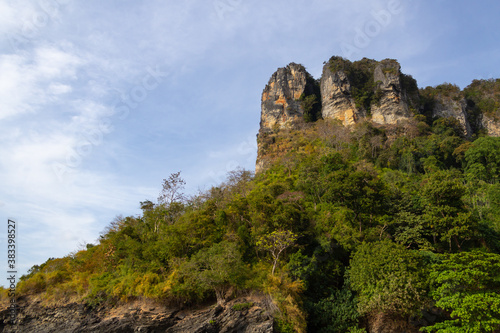 mountains and rocks covered with trees against a blue sky with clouds. Thailand