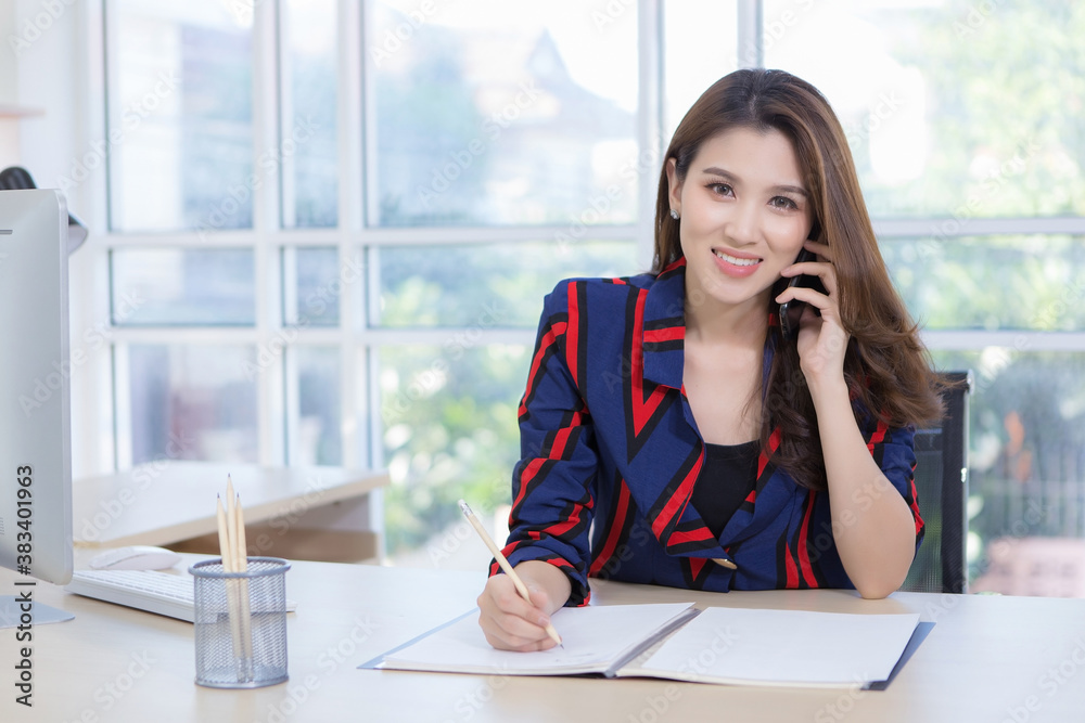 Beautiful Asian businesswoman holds a smartphone to talk about work.Work from home Beautiful Asian businesswoman holds a smartphone to talk about work.Work from home