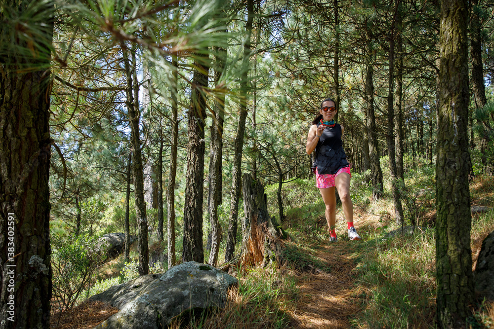 Atleta corriendo en un sendero de la montaña rodeada de arboles