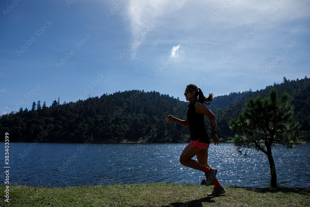 Obraz premium Atleta corriendo al aire libre cerca de un lago con montañas al fondo