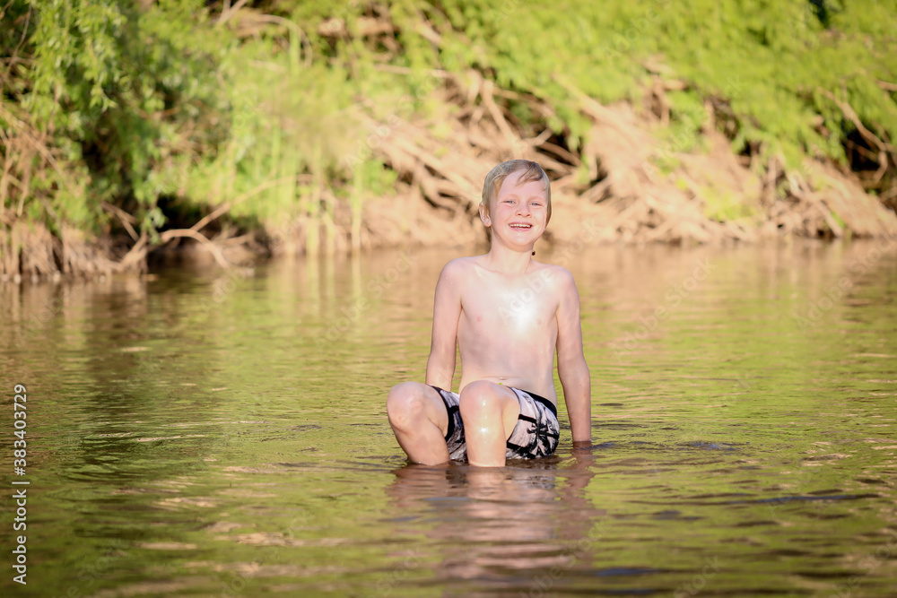 Boy swimming in fresh water river at dusk in New South Wales, Australia