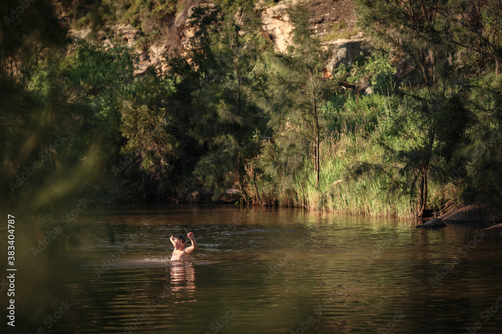 Boy swimming in river in beautiful afternoon light