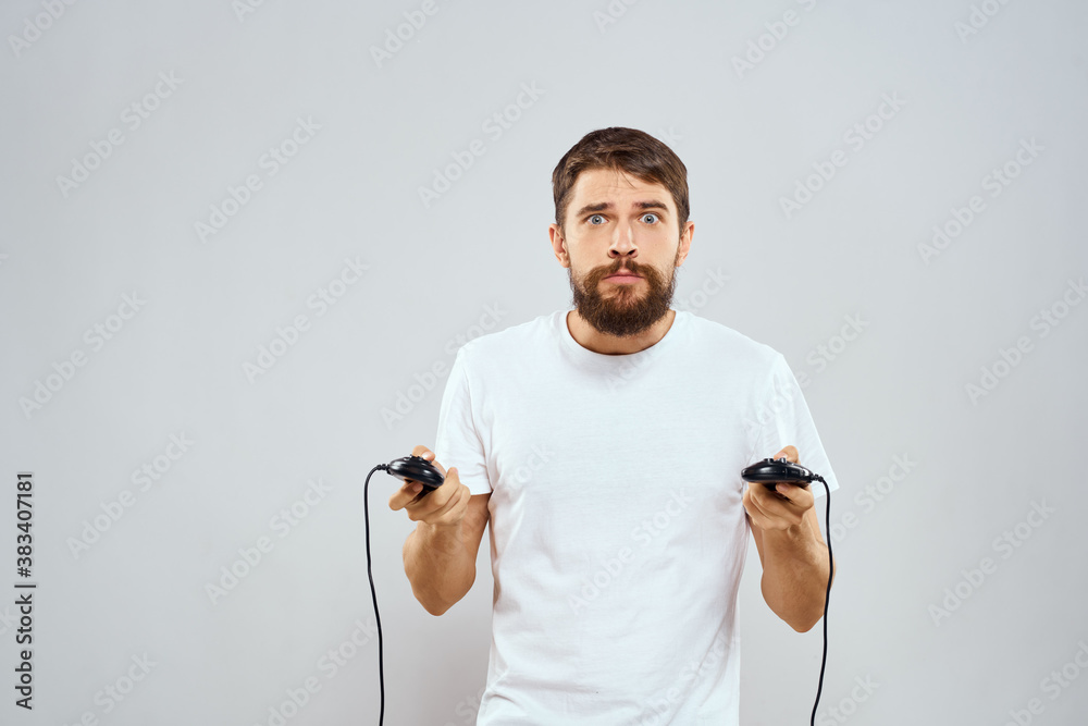 A man holds in his hands two joysticks playing leisure technology lifestyle white t-shirt A man holds in his hands two joysticks playing leisure technology lifestyle white t-shirt