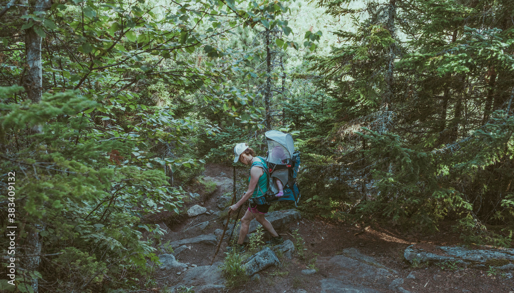 Woman hiking with a baby on a backpack moving among the rocks