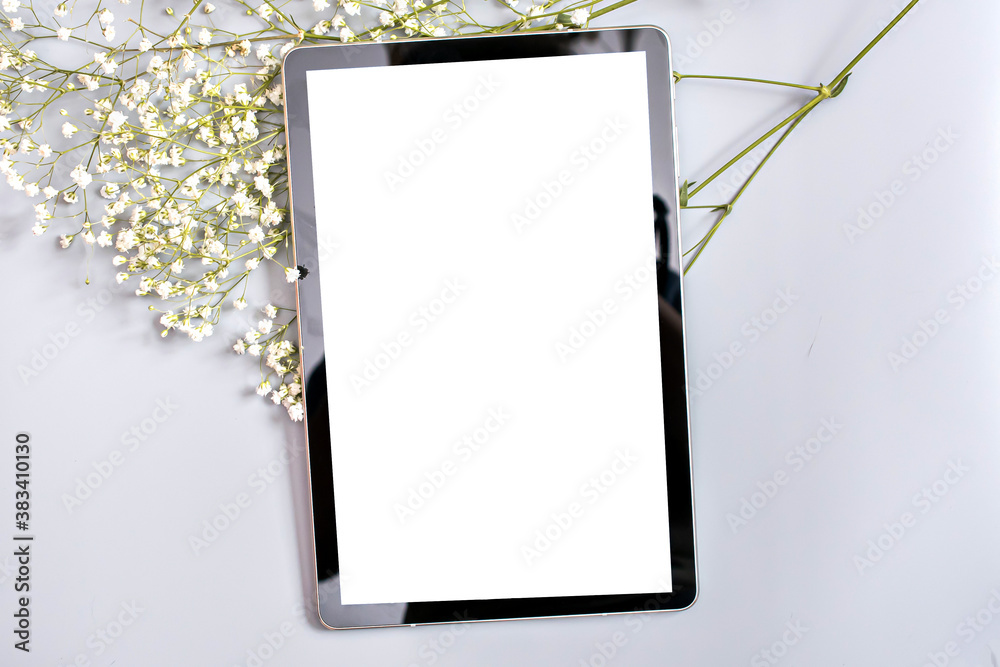 tablet with a place to insert on a gray background next to the white flowers of the gypsophila tablet with a place to insert on a gray background next to the white flowers of the gypsophila