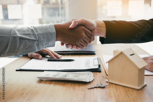 Home sales agents and buyers work on signing new homes and shaking hands.