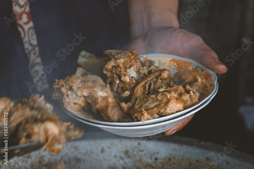 Spicy Tengkleng Gajah. goat meat with ribs and bone cooked with soup. Indonesian Traditional Food made from Barbecue Lamb's Bone isolated on black wood background photo