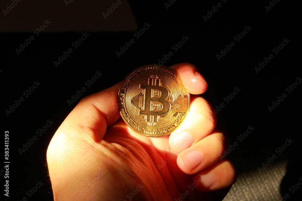 暗闇の中で黄金色に輝くビットコインを掴む手
暗闇の中で黄金色に輝くビットコインを掴む手