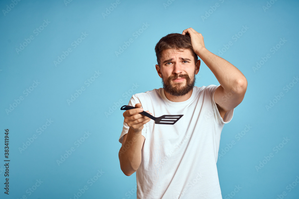 A man with a shovel for cooking in his hand on a blue background and a white T-shirt A man with a shovel for cooking in his hand on a blue background and a white T-shirt