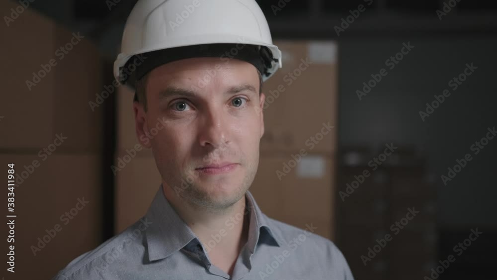 Man in a hard hat in a warehouse on the background of cardboard boxes Man in a hard hat in a warehouse on the background of cardboard boxes