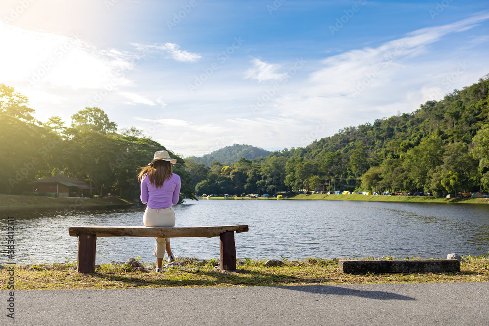 Social distancing, a woman is sitting alone by the lake.
