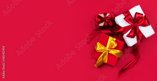 Christmas gift boxes with red and gold ribbons on a red banner background. Christmas and new year banner. Flat lay, top view, copy space, banner