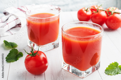 Wallpaper Mural Tomato juice in glass glasses and fresh ripe tomatoes on a branch. White wooden background with copy space. Torontodigital.ca