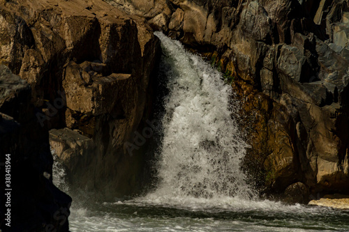 Close up view of the cascading water at great falls region of the potomac river. Image was taken from a scenic overlook at Great Falls park in virginia. Water sparkles as it moves fast throug rocks.