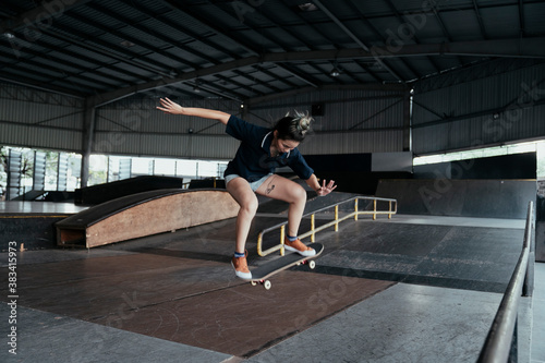 Skateboard player woman doing jump flip.