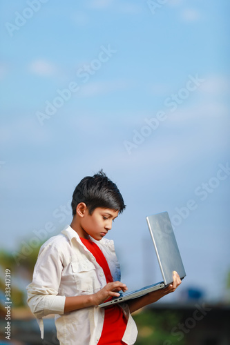 Cute little Indian/Asian boy studying or playing game with laptop computer