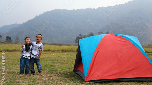 Two happy boys kids outside the tent hugging each other. Asian kids at Camping ground.