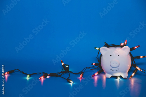 White piggy bank with Christmas string lights on happy December festival, Enjoy savings for spending money on the holiday's concept