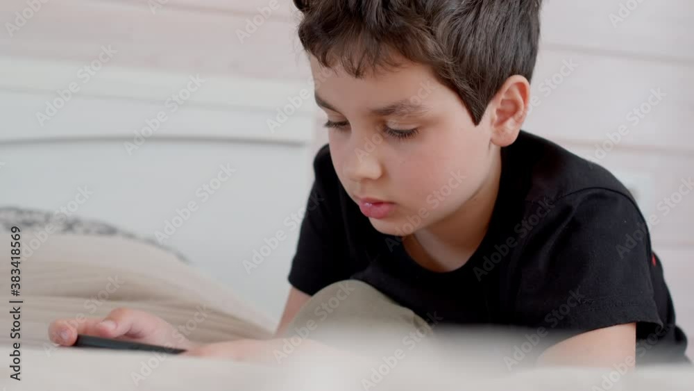 Cute teenager with a smartphone at home. Boy plays on a mobile phone at home. 