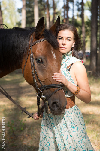 Young beautiful woman walking in the forest with her horse 