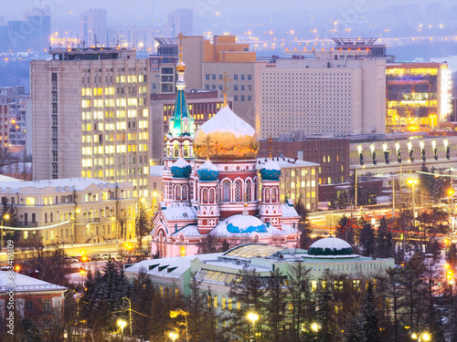 Assumption Cathedral in the center of Omsk. Holy Assumption Cathedral from a height in the winter evening, the city is illuminated by lights.