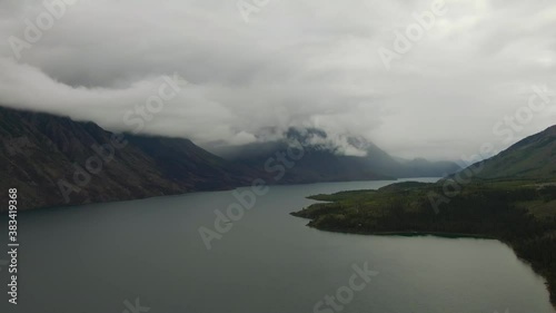 Beautiful View of Scenic Lake surrounded by Mountains and Trees on a Cloudy Day. Aerial Drone Shot. Southern Yukon, Canada. photo