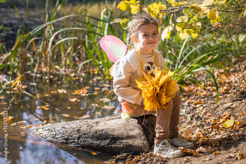 Obraz na płótnie Happy little young girl with a bouquet of yellow and orange leaves resting and walking in nature in the autumn forest near the lake in Moscow region of Russia with yellow and orange autumn leaves w salonie