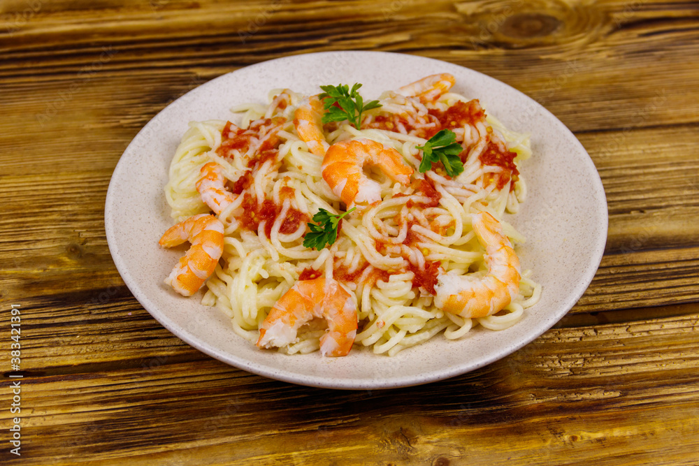 Spaghetti pasta with prawns, tomato sauce and parsley on wooden table Spaghetti pasta with prawns, tomato sauce and parsley on wooden table
