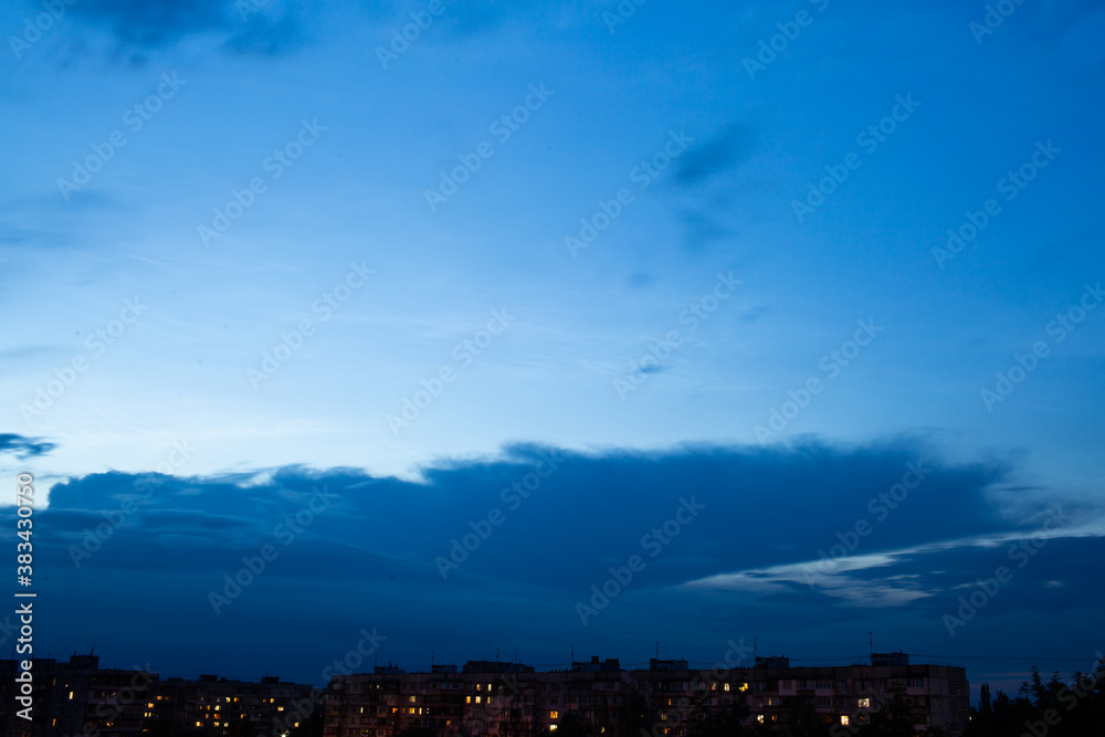 In the dark blue sky, only silhouettes of houses are visible. sunset sky over the roof of the house with small suburban houses on a horizontal line. In the dark blue sky, only silhouettes of houses are visible. sunset sky over the roof of the house with small suburban houses on a horizontal line.