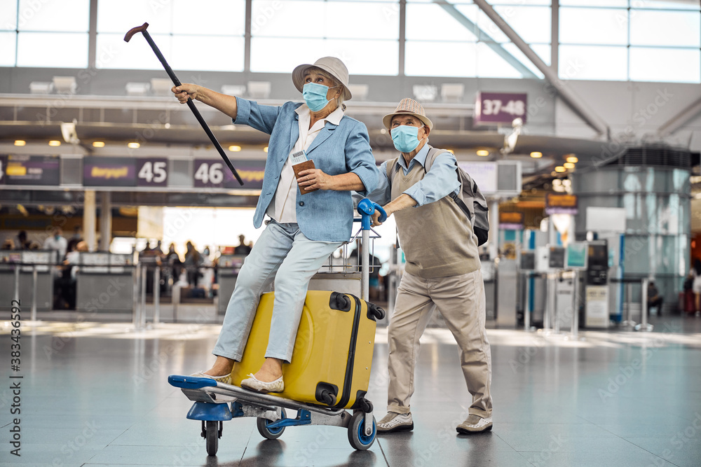 Fototapeta premium Male pensioner wheeling his wife on a baggage trolley