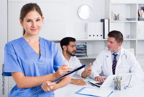 Young doctor assistant standing in medical office noting prescriptions