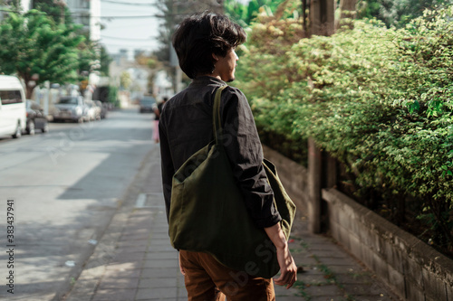 Man carrying a canvas bag walking on street. photo