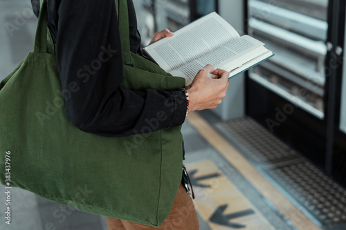 Close up hand of man reading a book at train station.