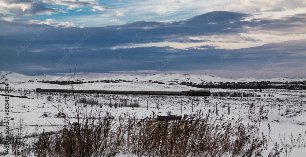 Passenger train. Snow steppe. Passenger transportation. Grunge landscape. Kazakhstan, outskirts of Ust-Kamenogorsk