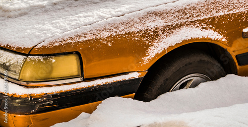 Car closeup. Fragment. Old car under the snow. Abandoned. Winter snow. Yellow